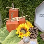 Herbstdekoration von Angelika mit orangefarbenen Holzkürbissen und Sonnenblumen